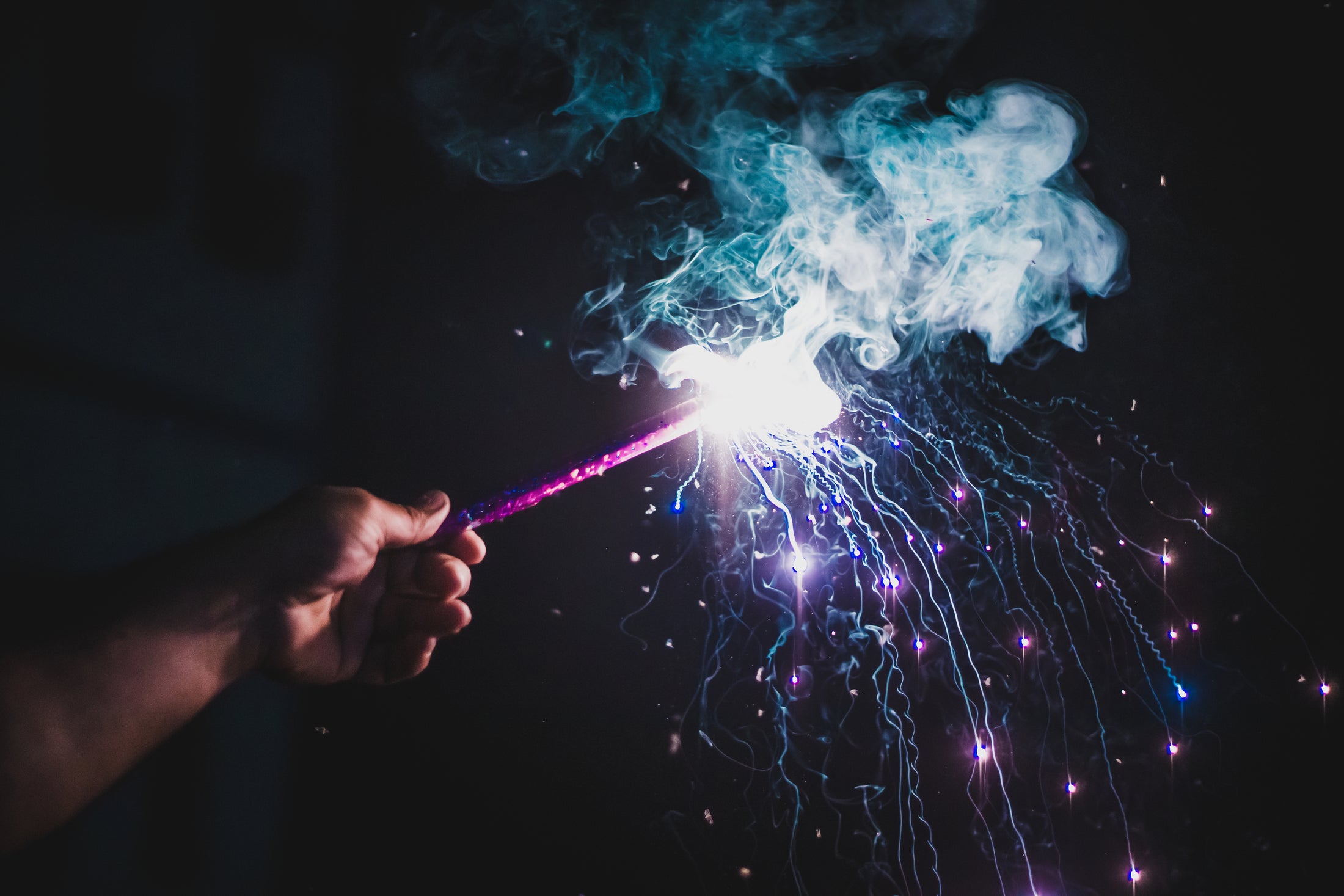A handheld firework producing bright light and colored smoke